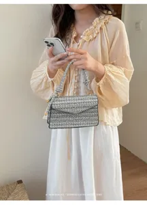 Primo piano di una piccola borsa quadrata testurizzata grigio e nero con manico