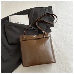 Borsa a secchiello marrone in finta pelle con cinturino decorativo in un contesto casual