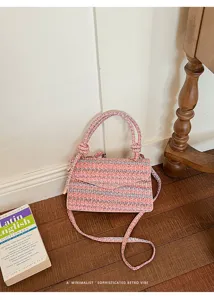 Dettaglio di una borsa a tracolla intrecciata rosa e blu in un ambiente stile retrò
