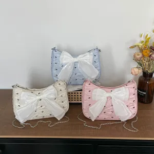 Group of three seersucker shoulder bags in pastel colors with large white bows on a table