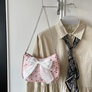 Stylish pink seersucker underarm bag featuring a large white bow and silver chain strap.