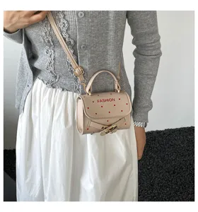 Small beige crossbody bag featuring red polka dots and FASHION lettering detail.