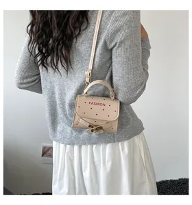 Rear view of a model carrying a beige polka dot crossbody handbag with red buckle detail.