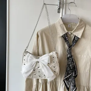 Detail view of stylish bubble gauze underarm bag with a large white organza bowknot