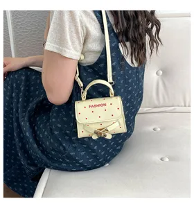 Cream polka dot handbag with red FASHION text and gold buckle detail shown on a model