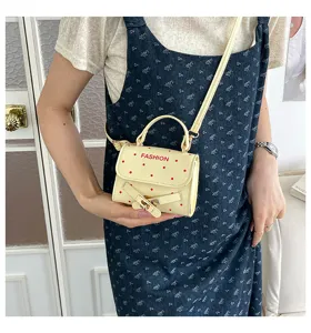 Detail view of a cute polka dot mini crossbody bag with buckle, styled on a model.