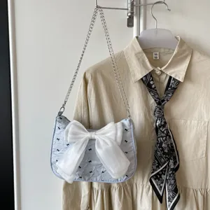 Detailed view of light blue seersucker shoulder bag with a large white bow