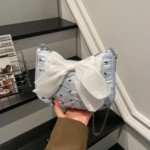 Close-up of a light blue seersucker shoulder bag featuring a large white organza bow detail.