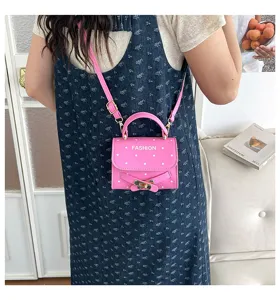 Detailed view of pink polka dot small square bag with fashion print and gold buckle