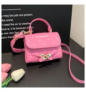 Close-up of pink polka dot square bag with decorative buckle and 'FASHION' text