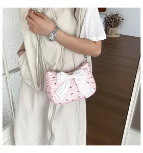 Detail view of pink bubble gauze shoulder bag with large white bow and chain strap