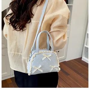 Detailansicht einer hellblauen gepunkteten Handtasche mit cremefarbener Spitze und Schleifen