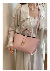 Vista detallada del bolso tipo cubo de cuero rosa con cierre dorado llevado por una modelo
