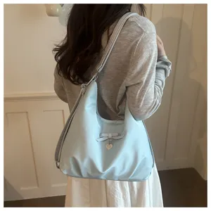 Detail view of sky blue large capacity shoulder bag featuring a cute bow and heart pendant