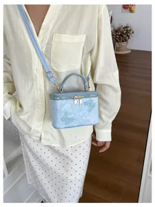 Dettaglio della borsa a mano celeste in jacquard con delicate applicazioni di farfalle 3D