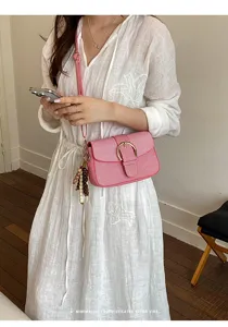 Detail view of pink textured crossbody bag worn by model in white dress lifestyle shot