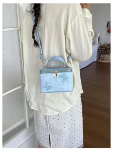 Elegante borsa a mano a scatola azzurra con ricamo a farfalla indossata da una modella