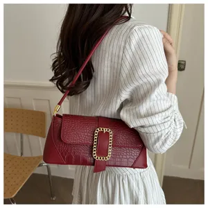Close-up of a burgundy stone-patterned baguette shoulder bag on a model