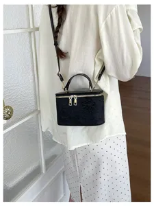 Vista macro di una borsa a mano nera con squisito jacquard a farfalla e dettagli oro