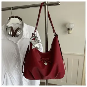 Detail view of the red hobo bag featuring a bow, heart charm, and silver star pendant