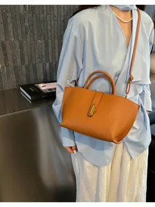 Primer plano del bolso de piel color camel con cierre metálico dorado y correa