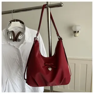 Detailed view of red large-capacity shoulder bag with heart charm and bow decoration