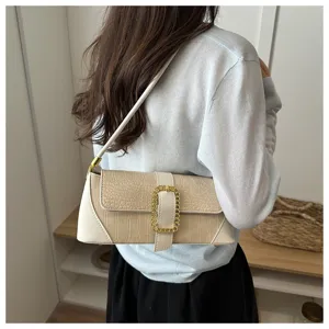 Elegant beige crocodile pattern baguette shoulder bag worn by a woman, back view detail