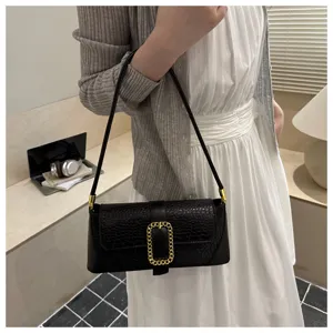 Detailed shot of a black croc-embossed underarm baguette bag with a golden buckle