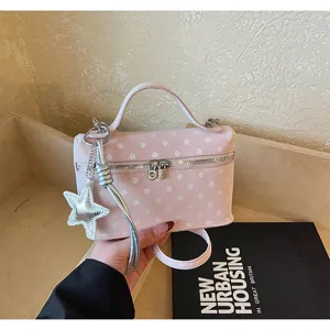 Detail of pink polka-dot box bag with silver star pendant and zipper closure