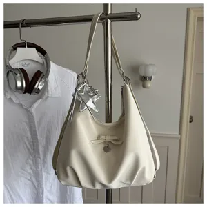 Detailed view of cream hobo bag with elegant bow and star charm hanging on a rack