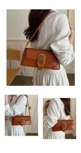 Brown faux leather baguette underarm bag with stone pattern and gold buckle worn by model
