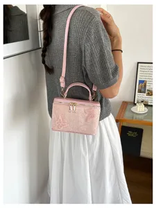 Dettaglio della borsa a mano rosa in jacquard con farfalle indossata da una modella