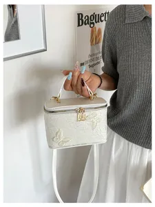 Vista dettagliata del delicato ricamo a farfalla su questa borsa box in jacquard bianco.