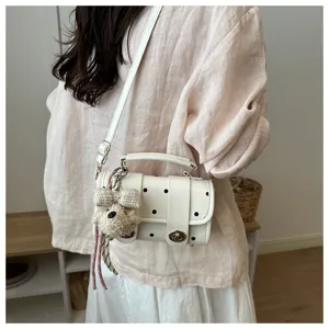 Charming white polka dot pillow handbag with cute plush charm accessory shown on model