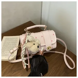 Detailed view of pink polka dot pillow bag with cute plush bear charm on wooden table