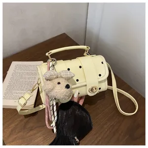 Close-up of cute yellow polka dot pillow bag with fluffy puppy charm and gold clasp