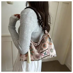 Vista dettagliata della borsa tote rosa ricamata con tracolla in legno e nappa