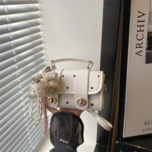 Chic white polka dot pillow handbag featuring a cute bunny charm and elegant gold hardware