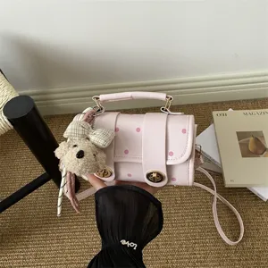 Stylish pink polka dot pillow bag for women featuring a cute teddy bear charm accessory