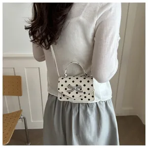 Vue arrière d'un mannequin portant un mini sac carré à pois avec un nœud en cristal