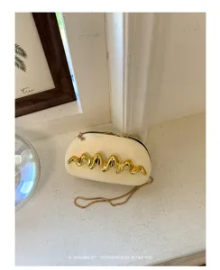 Vista dettagliata di una pochette da sera bianco panna con un accento metallico dorato a onde