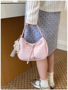 Detailansicht einer rosa Schleifen-Handtasche mit Perlenanhänger im Pendler-Stil.