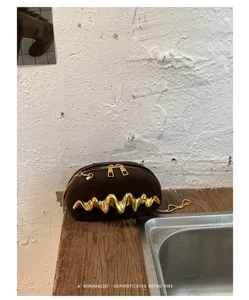 Dettaglio di una borsa da sera minimalista in pelle scamosciata marrone con decoro in metallo dorato
