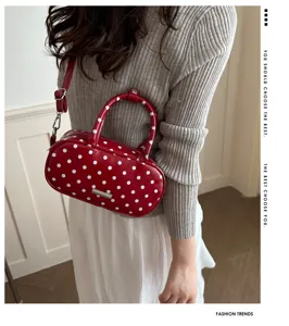 Rode polkadots ovale handtas gedragen door model in grijze geribbelde trui
