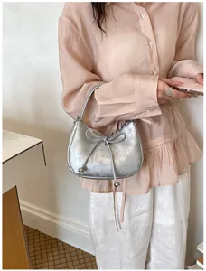 Nahaufnahme einer silbernen Metallic-Hobo-Tasche mit Schleife an einem Model