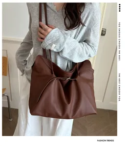 Close-up detail of a minimalist brown pebbled leather tote bag with stylish shoulder straps