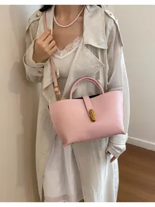 Elegante bolso tote de cuero rosa con cierre dorado mostrado en una modelo con abrigo