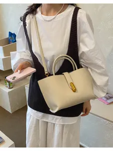 Detalle de un bolso tote vintage de cuero crema con cierre dorado usado por modelo