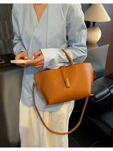 Bolso tote grande de cuero marrón con correa para el hombro mostrado por una modelo en un entorno
