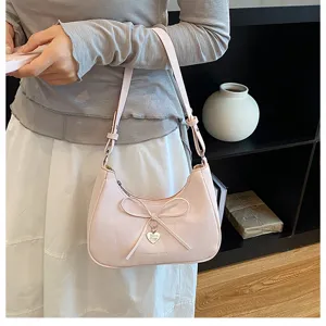 Gros plan détaillé de l'élégant sac hobo rose avec un nœud et un pendentif coeur